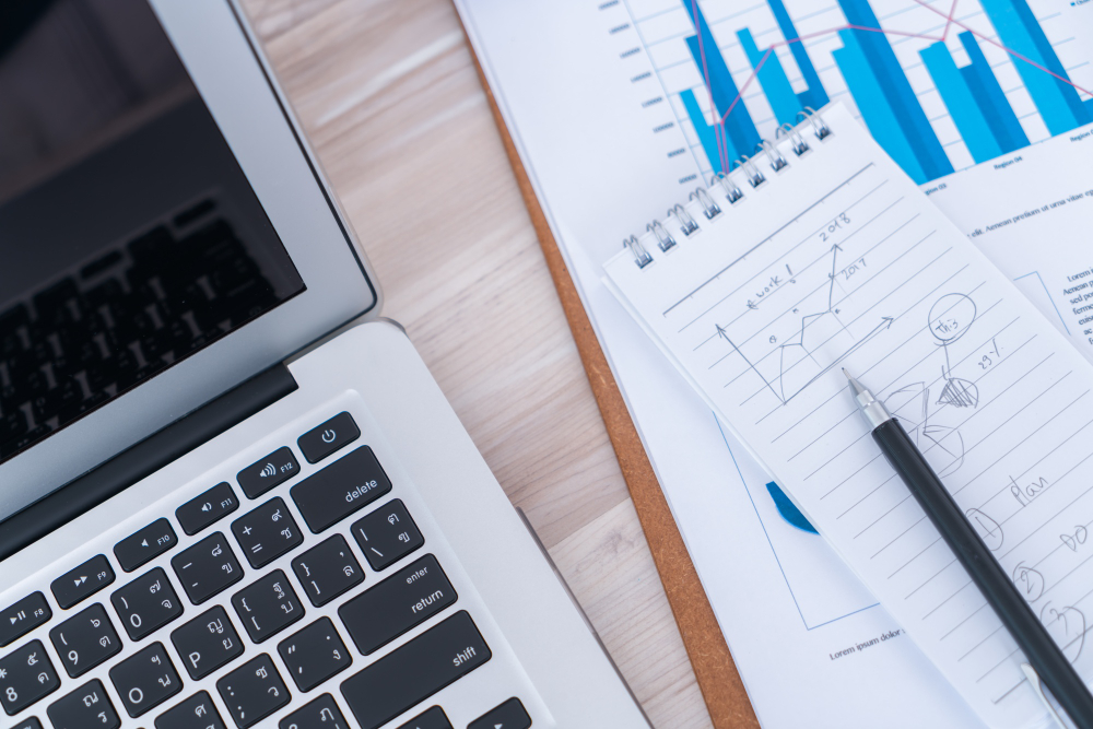 Financial charts on the table next to a laptop